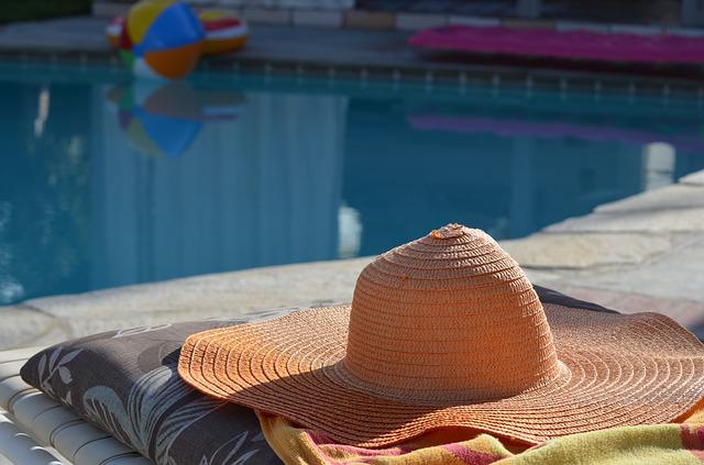 hat and towel next to pool