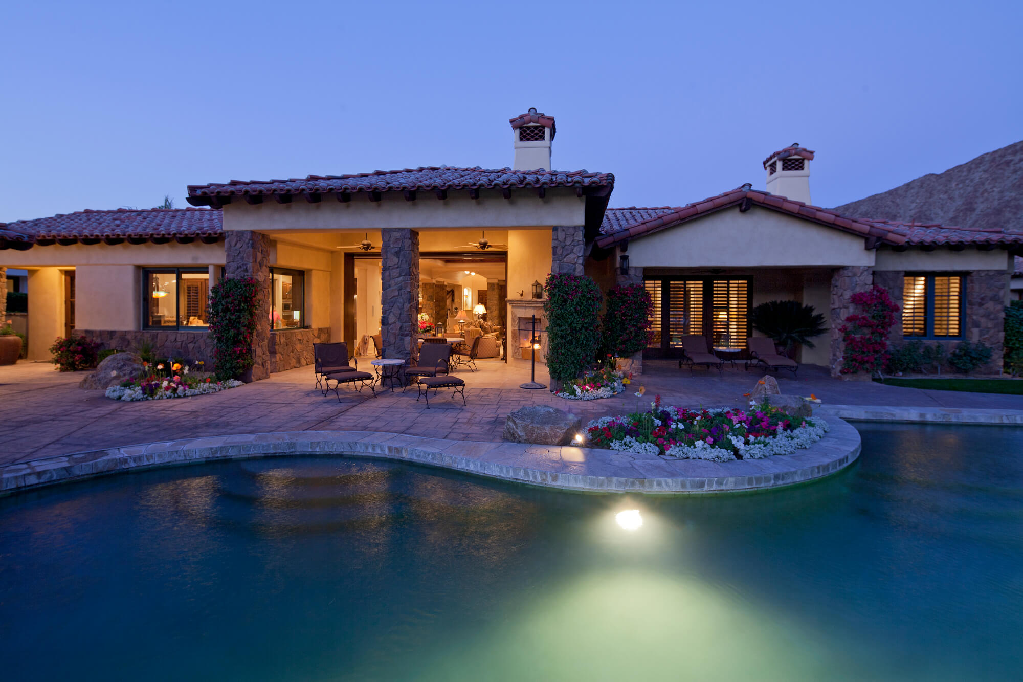 Luxury home with outdoor pool and patio area at twilight