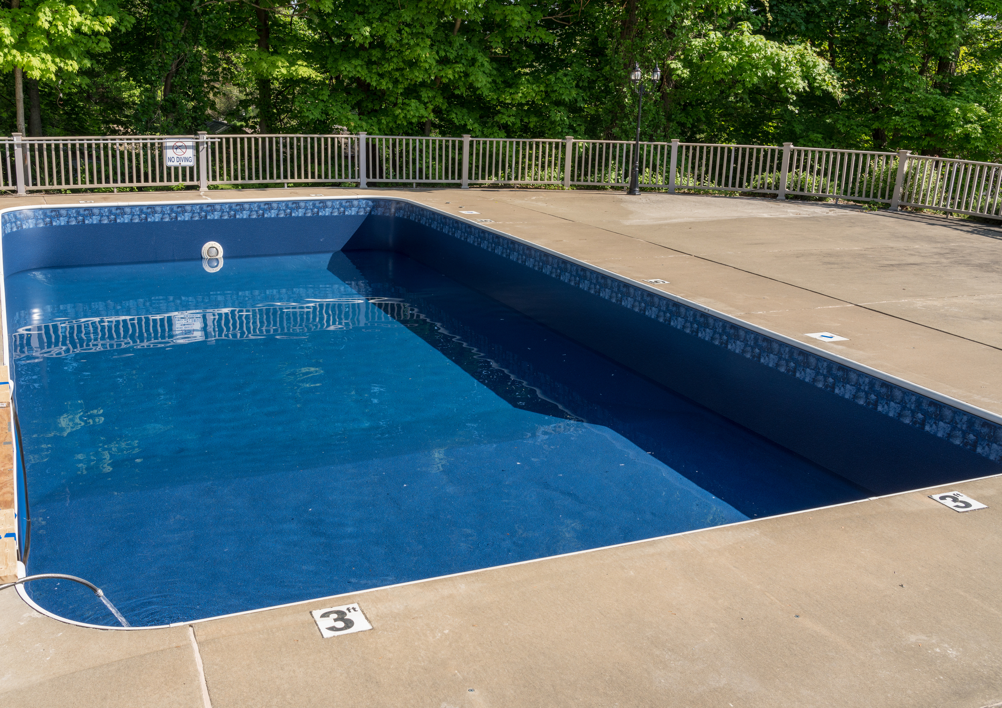 Outdoor swimming pool with clear blue water and depth markers on the pool deck