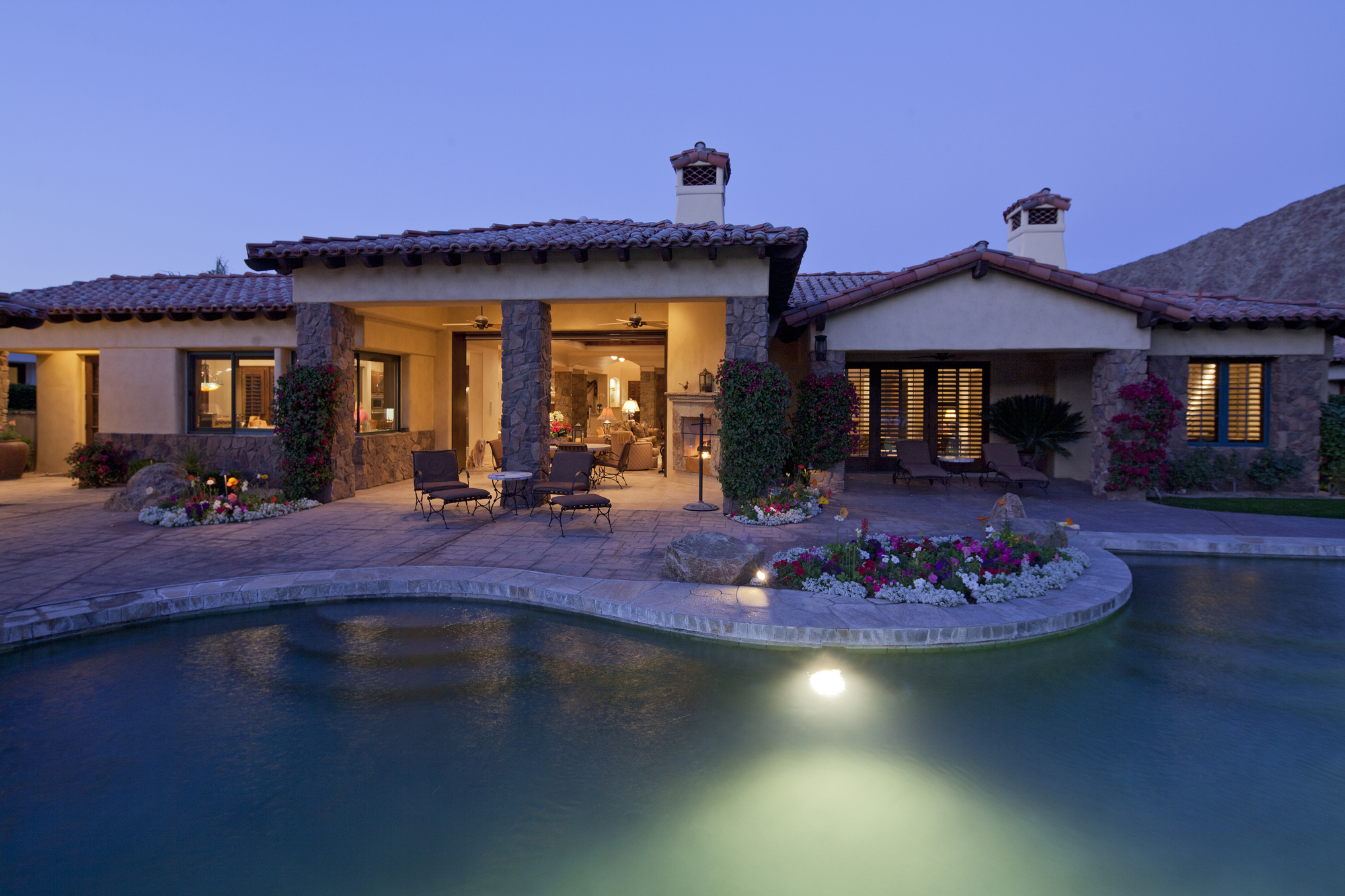 Luxury home with outdoor pool and patio area at twilight