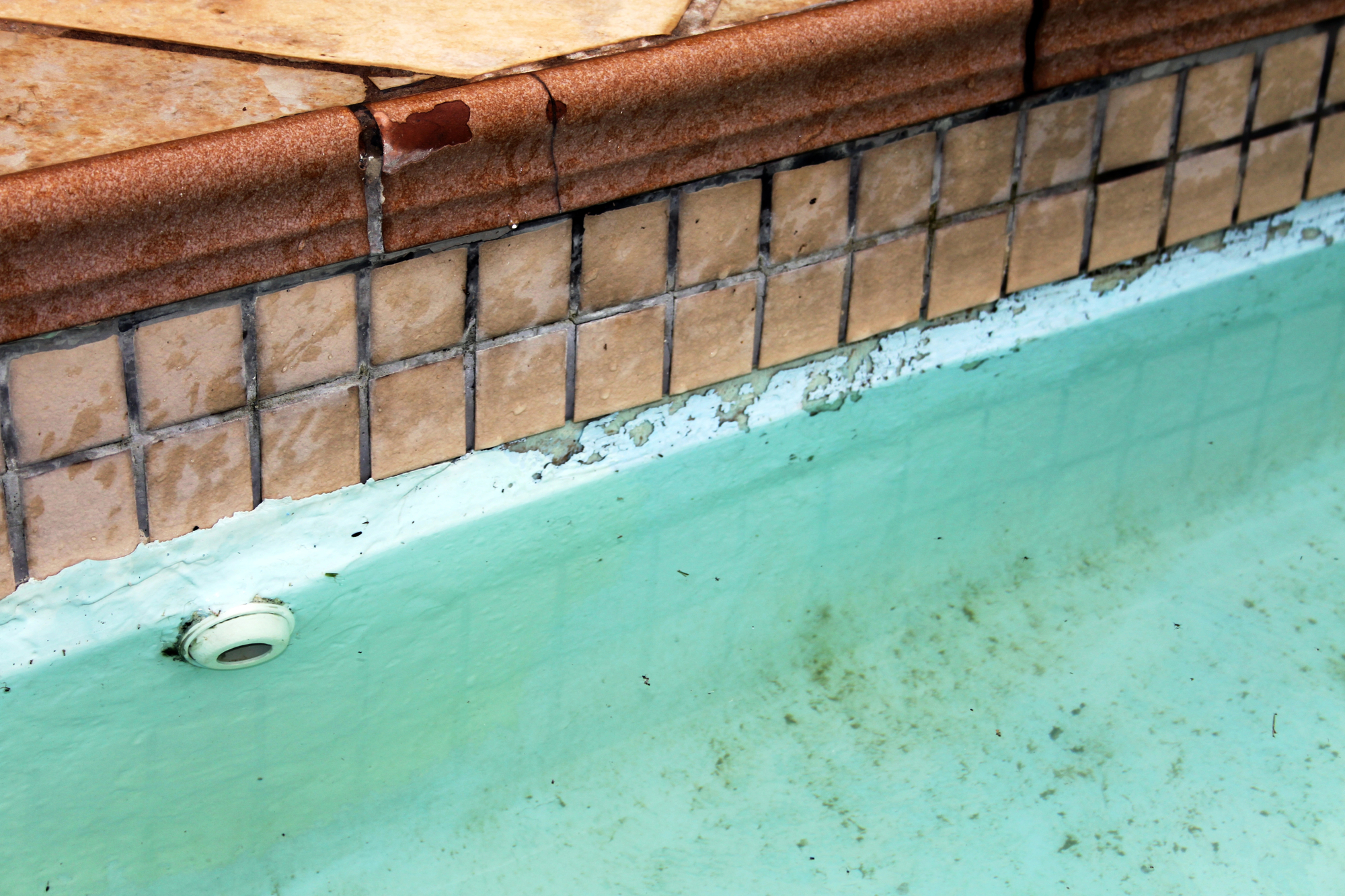 Visible damage and discoloration on swimming pool tiles indicating potential leakage