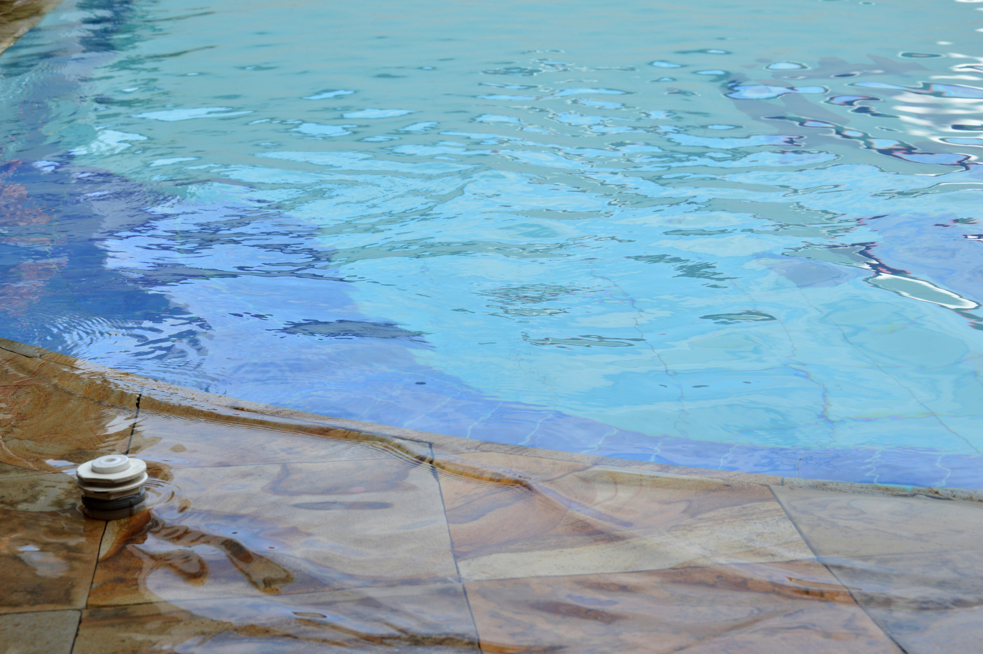 A close-up of a pool edge with a clean waterline and intact tiles, illustrating a well-maintained swimming pool